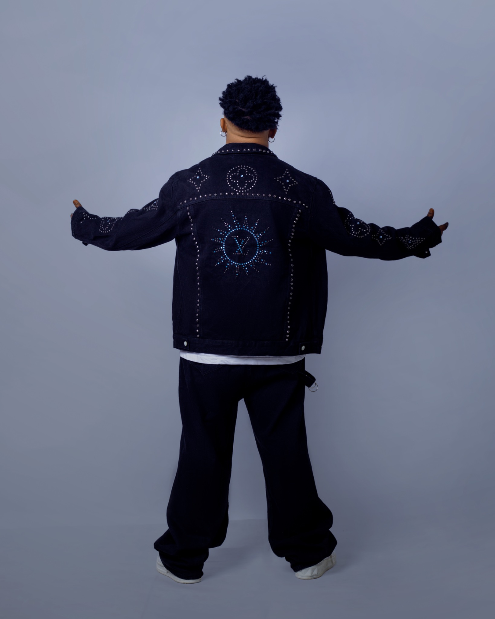 Oluwa Zizzle showing the back detail of his studded denim jacket