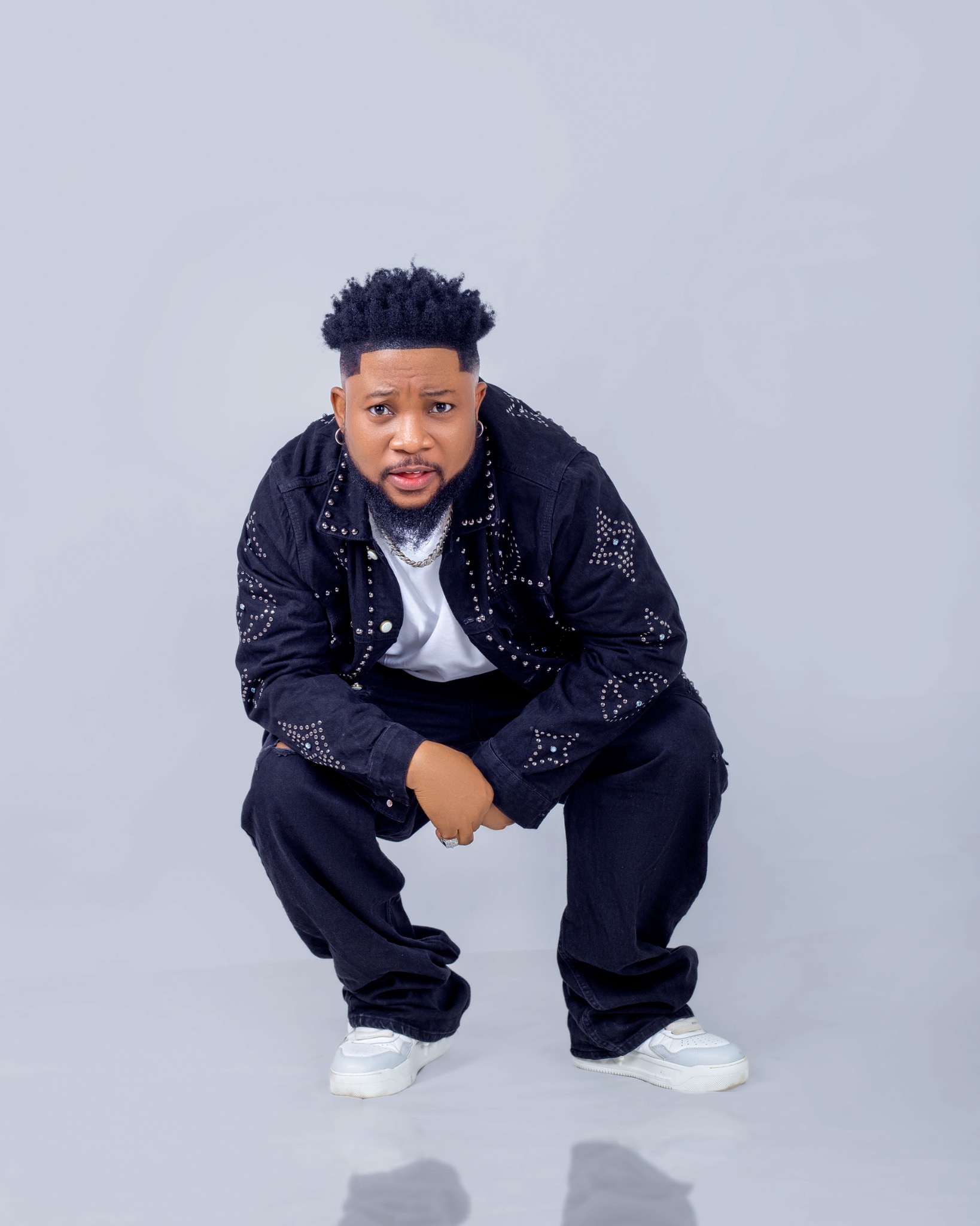 Oluwa Zizzle in a black studded denim outfit, front-facing portrait